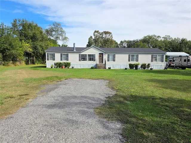 a front view of a house with a yard and trees
