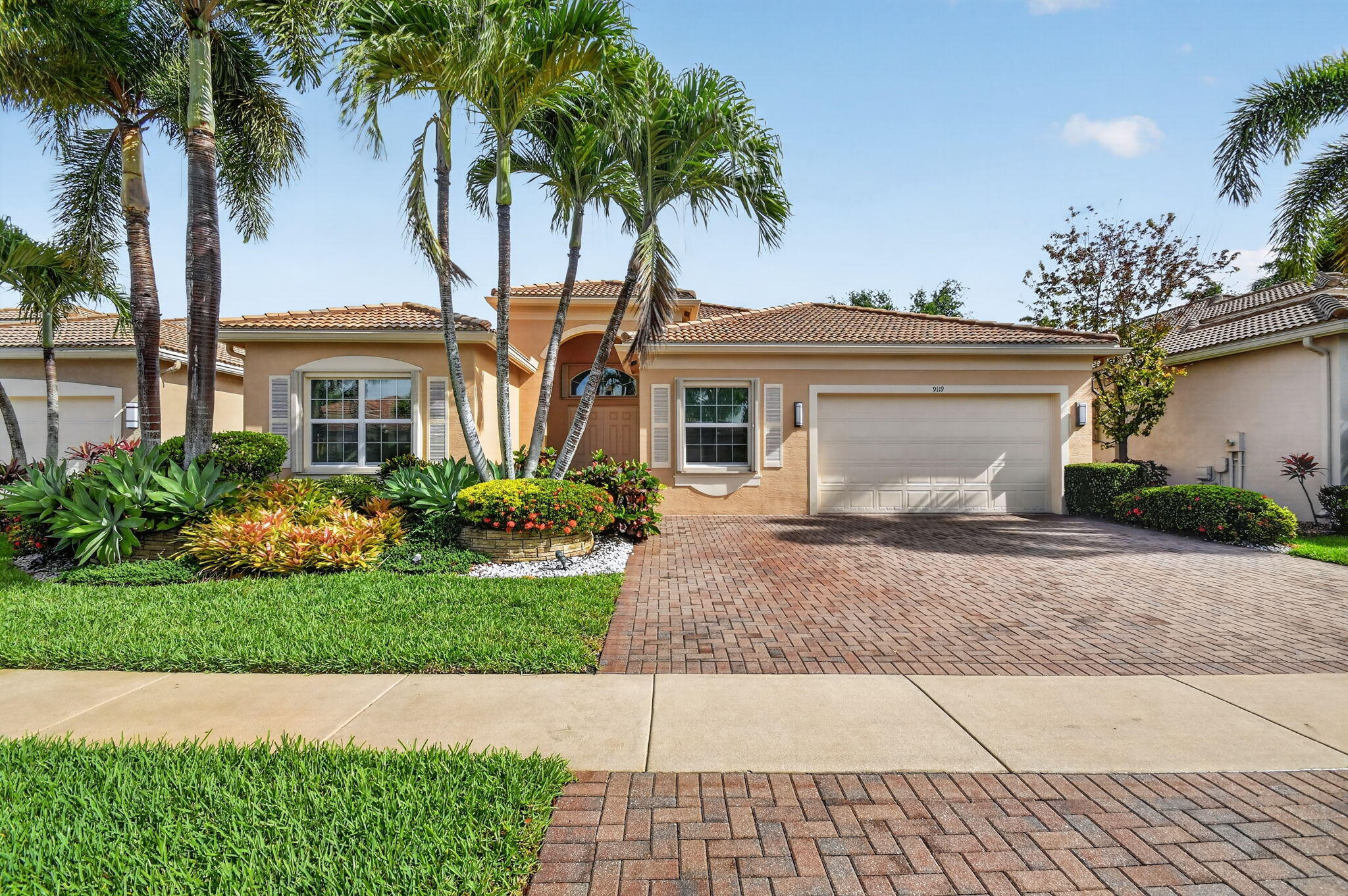a front view of a house with a garden and palm trees