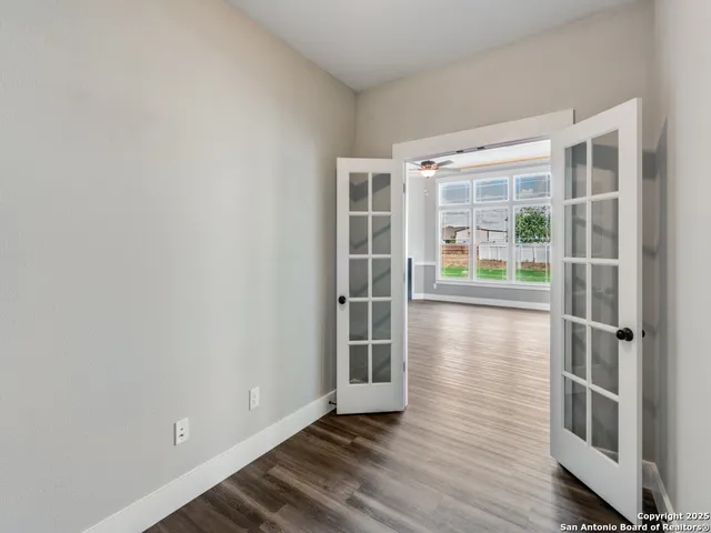 an empty room with wooden floor and windows