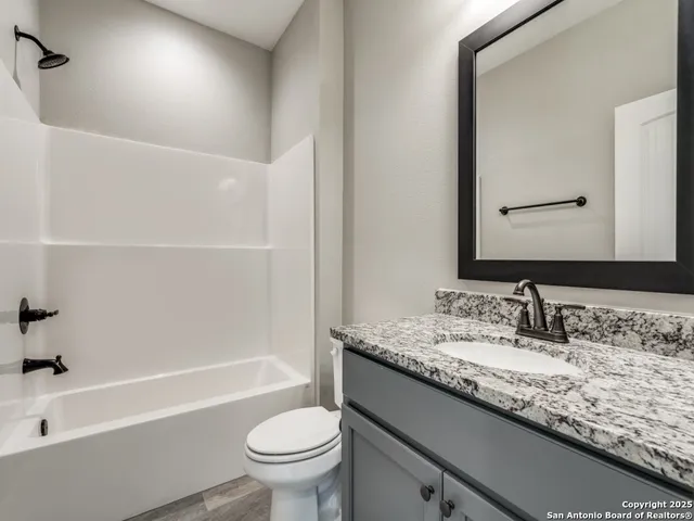 a bathroom with a granite countertop sink a toilet and bathtub