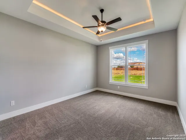 an empty room with windows and ceiling fan