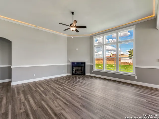 a view of empty room with wooden floor and fan