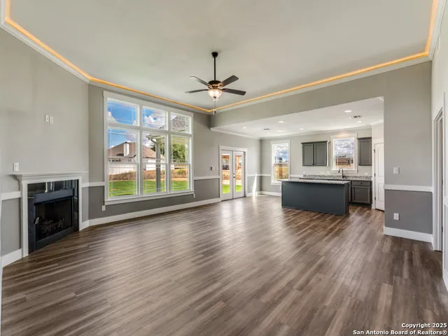 a view of a kitchen with furniture a ceiling fan and wooden floor