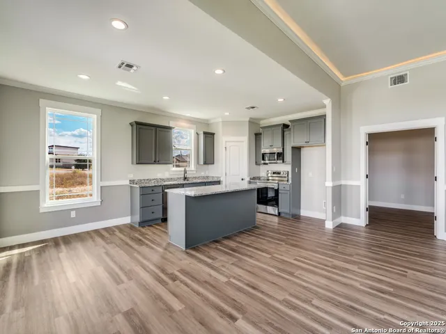 a large kitchen with stainless steel appliances granite countertop a large counter top and a stove top oven