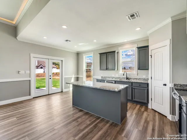 a kitchen with kitchen island granite countertop a sink appliances cabinets and wooden floor
