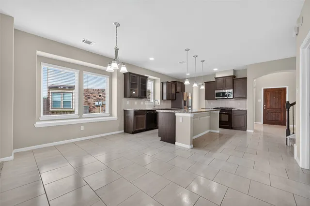 a open kitchen that has a refrigerator stove top oven a sink and dishwasher with granite countertop cabinets