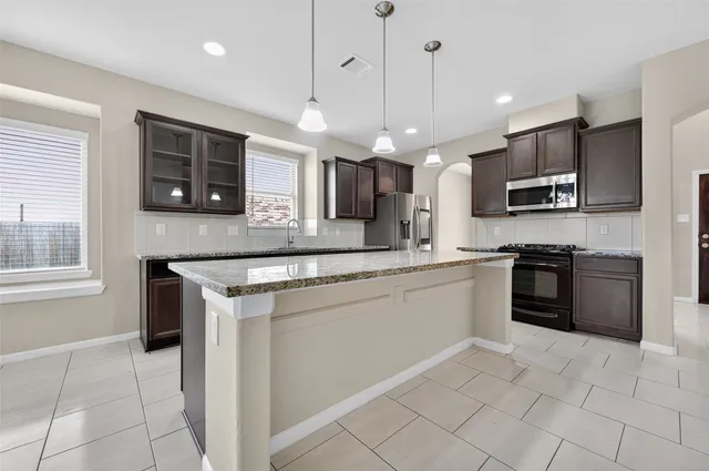 a large kitchen with a center island and stainless steel appliances