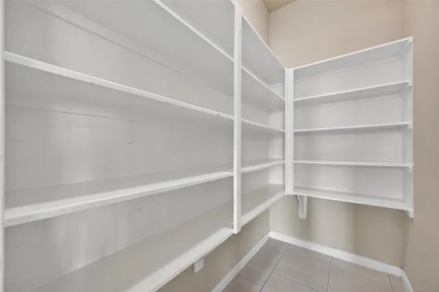 an empty room with chandelier fan and windows