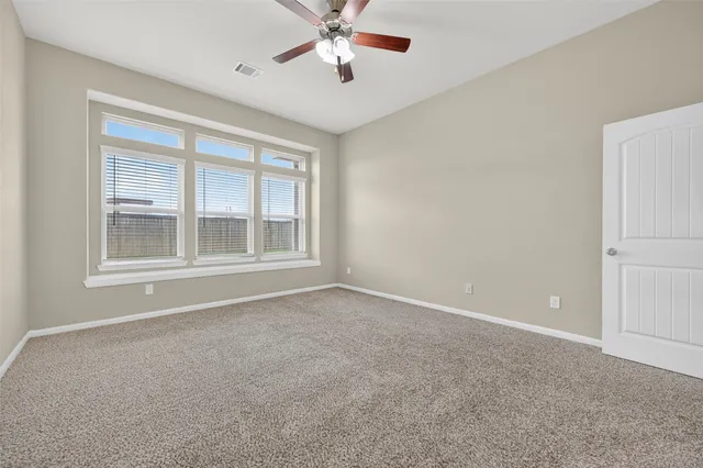a view of an empty room and chandelier fan