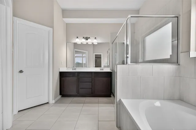 a bathroom with a bathtub shower sink vanity and mirror