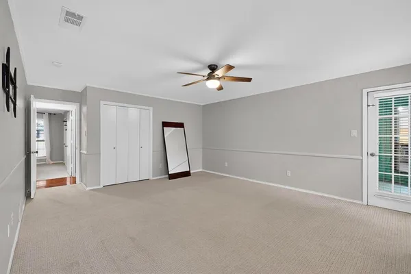 an empty room with closet and a ceiling fan