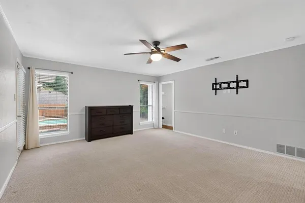 an empty room with windows and ceiling fan