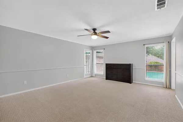 an empty room with windows and ceiling fan