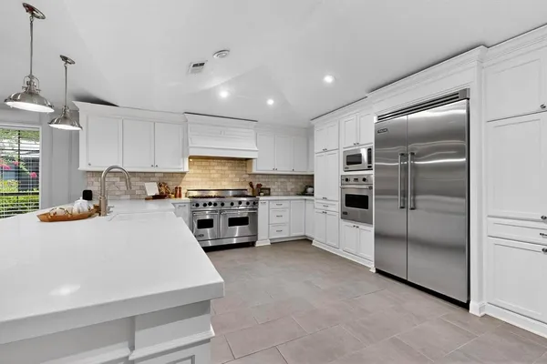 a kitchen with granite countertop a refrigerator and a stove top oven