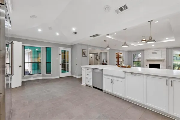 a large white kitchen with a sink a window and stainless steel appliances