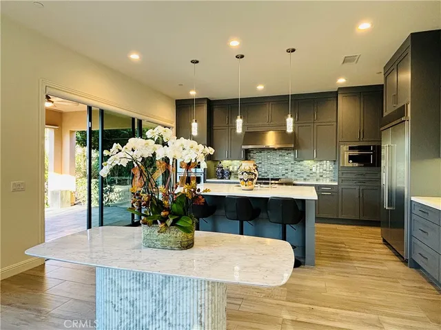 a kitchen with stainless steel appliances kitchen island granite countertop a refrigerator a sink a stove and a wooden floors