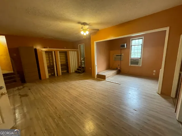 a view of an empty room with a window and wooden floor