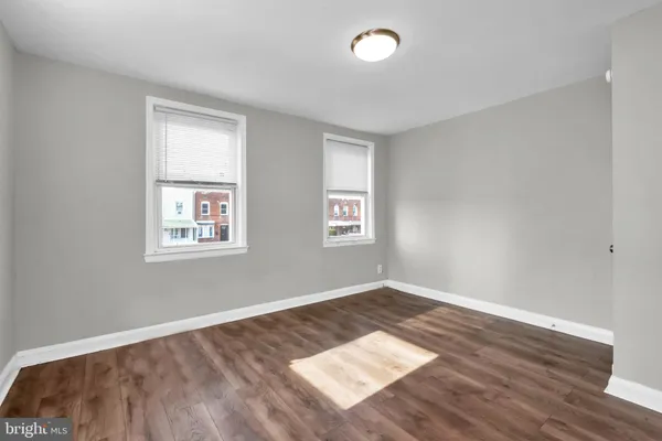 an empty room with wooden floor & windows