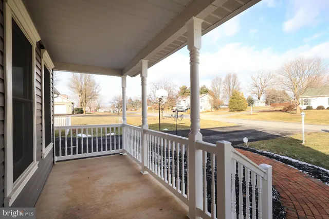 a kitchen with stainless steel appliances kitchen island granite countertop a stove top oven a sink a refrigerator and white cabinets with wooden floor