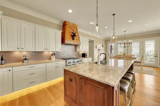 a large kitchen with kitchen island a stove a sink a center island and wooden floor