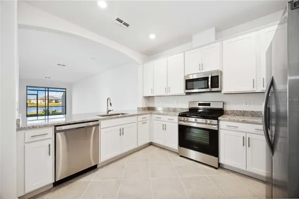 a kitchen with granite countertop white cabinets sink and stainless steel appliances