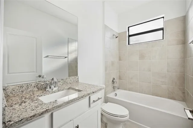a bathroom with a granite countertop sink a toilet and bathtub