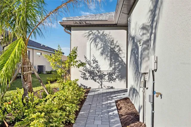 a view of a pathway of a house with a yard and potted plants