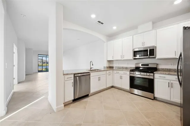 a kitchen with granite countertop white cabinets and stainless steel appliances