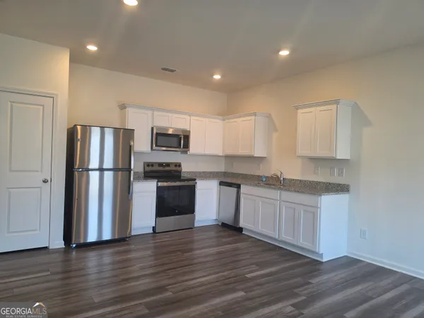 a kitchen with granite countertop a refrigerator and a stove top oven