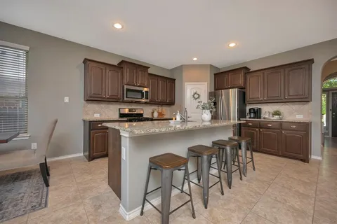 a kitchen with kitchen island granite countertop stainless steel appliances a sink a counter top space cabinets and a window