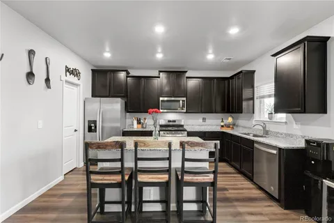 a kitchen with stainless steel appliances kitchen island granite countertop a table chairs microwave and sink