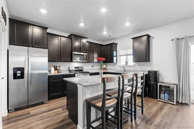 a kitchen with stainless steel appliances kitchen island granite countertop a refrigerator a stove a microwave oven a sink with island and chairs