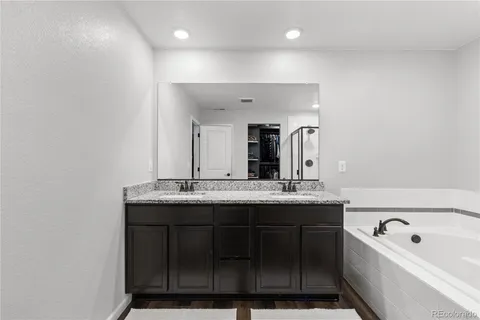 a bathroom with a granite countertop sink a large mirror and bathtub