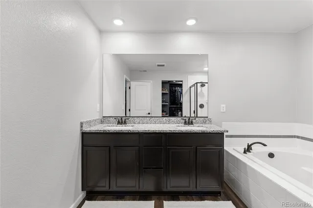 a bathroom with a granite countertop sink a large mirror and bathtub