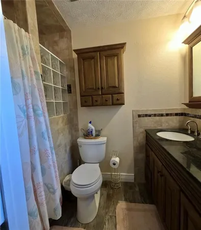 a bathroom with a granite countertop toilet sink and mirror