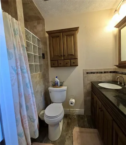 a bathroom with a granite countertop toilet sink and mirror