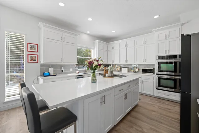 a kitchen with a sink white cabinets and stainless steel appliances