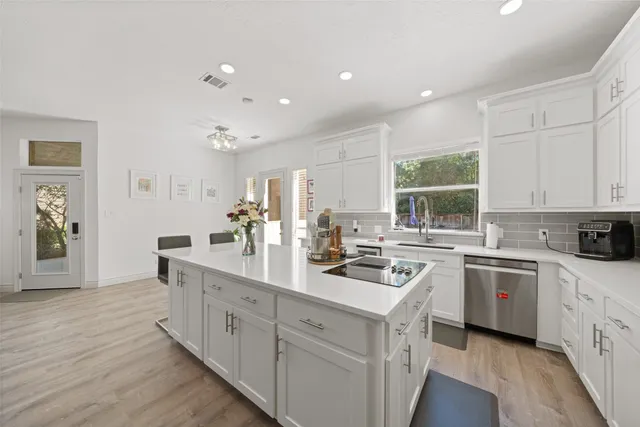 a kitchen with a sink stove cabinets and wooden floor