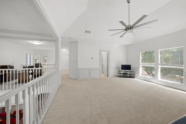 a view of a livingroom with wooden floor a ceiling fan and windows