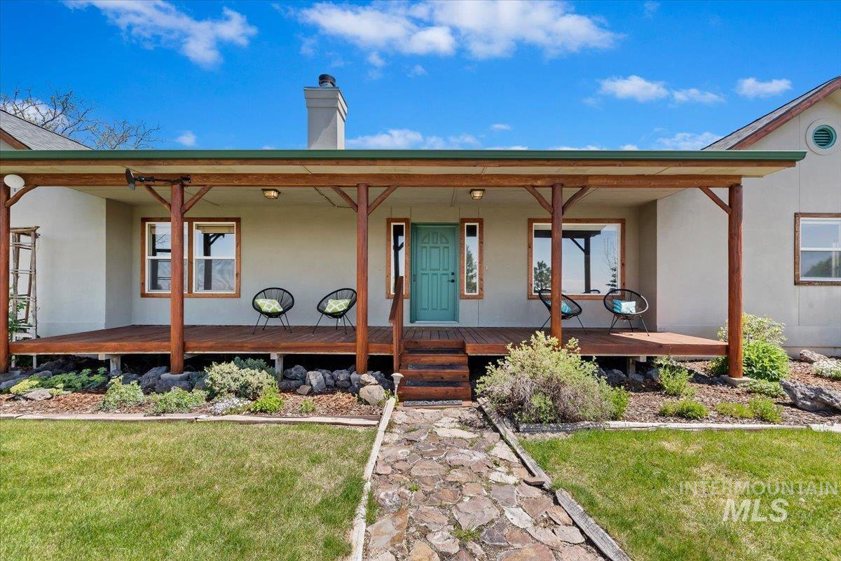 147 East Indian Crk Road Boise, ID 83716 - Photo 4 of 43 Exterior featuring a prominent wood-finish covered porch, a vibrant teal entry door, wood-frame windows, and a stone walkway
