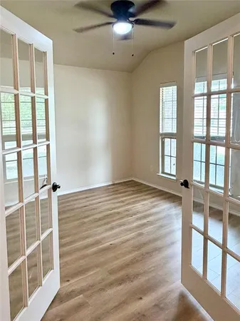 an empty room with wooden floor and windows