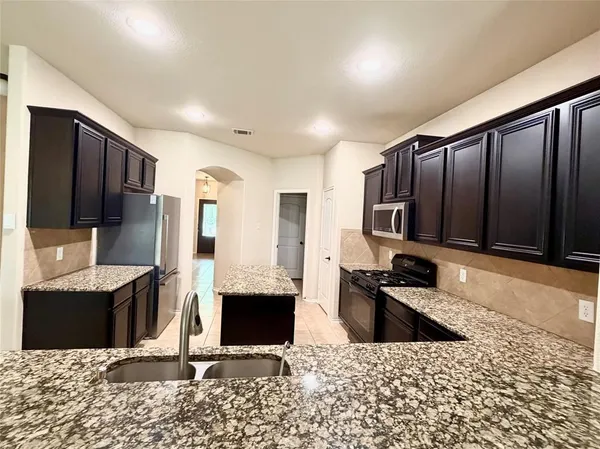 a kitchen with stainless steel appliances kitchen island granite countertop a refrigerator and a stove top oven