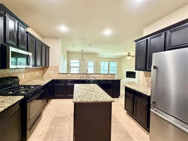 a kitchen with stainless steel appliances granite countertop a refrigerator a sink a stove and wooden cabinets