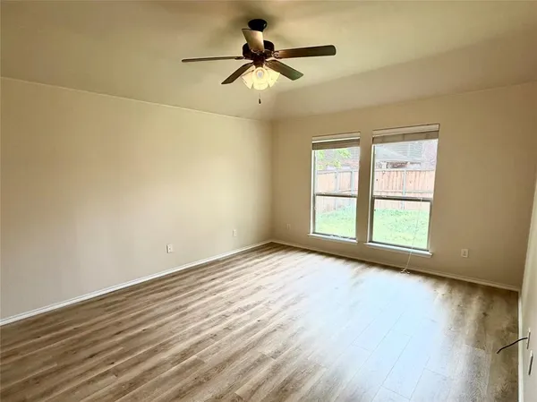 a view of an empty room with a window and wooden floor