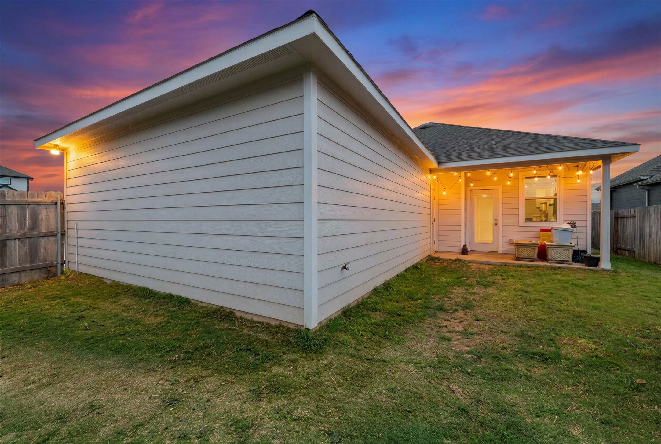 171 Acadia Drive Kyle, TX 78640 - Photo 12 of 26 View of back of home at dusk featuring a fenced backyard and a patio