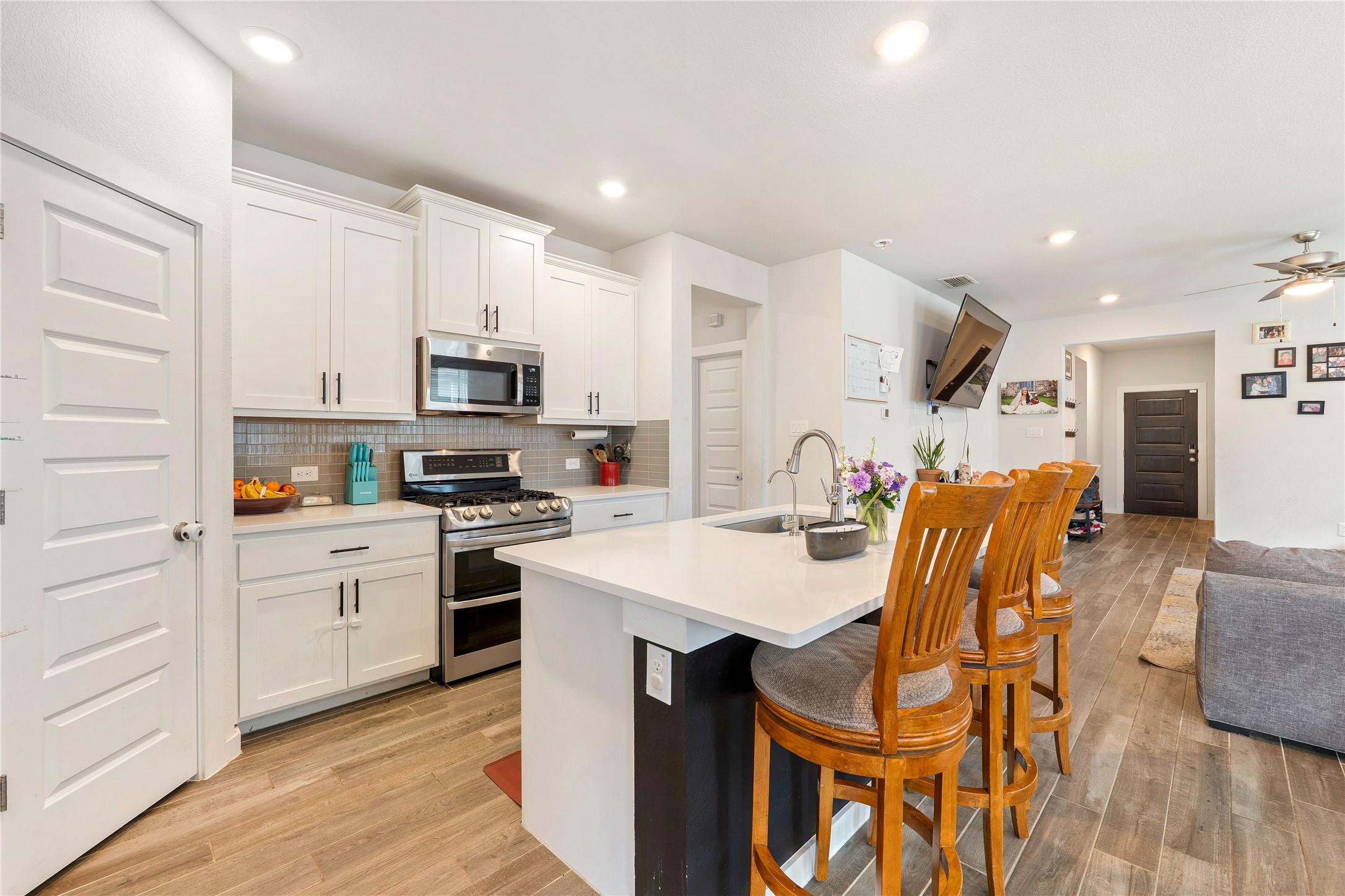 171 Acadia Drive Kyle, TX 78640 - Photo 25 of 26 Kitchen with open floor plan, stainless steel appliances, a kitchen bar, an island with sink, and white cabinetry