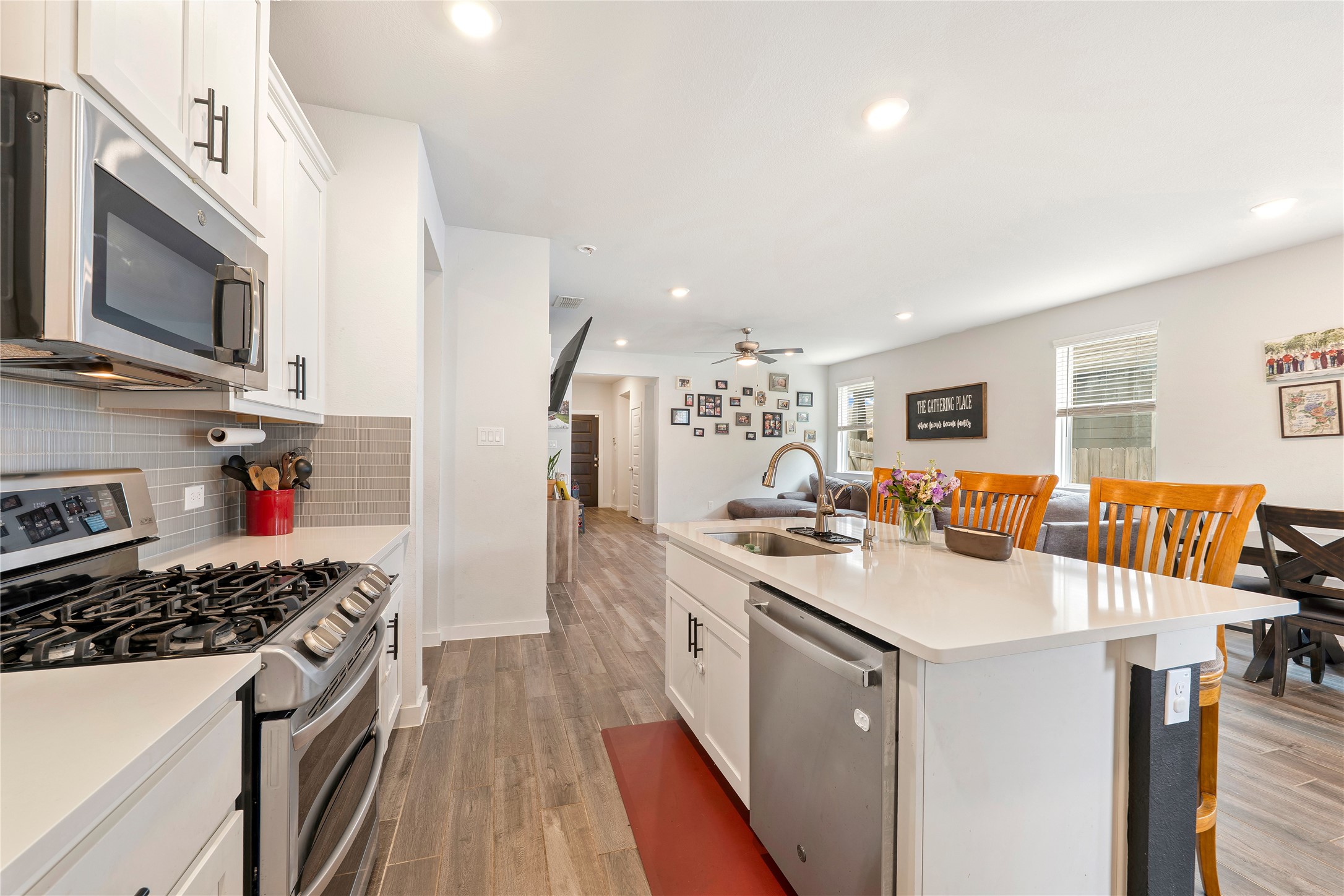 171 Acadia Drive Kyle, TX 78640 - Photo 9 of 26 Kitchen featuring stainless steel appliances, white cabinets, wood finished flooring, an island with sink, and recessed lighting