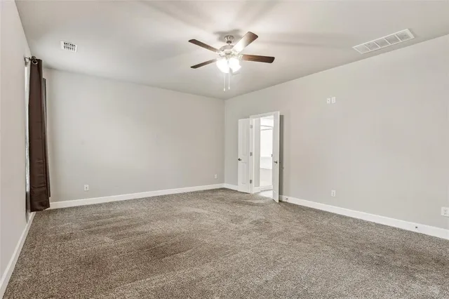 an empty room with closet and ceiling fan
