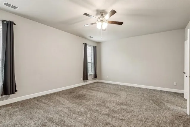 an empty room with a chandelier fan and windows