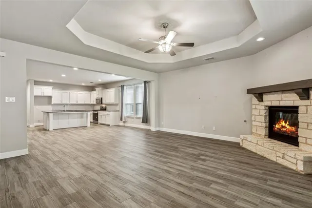 a view of an empty room with wooden floor and a kitchen